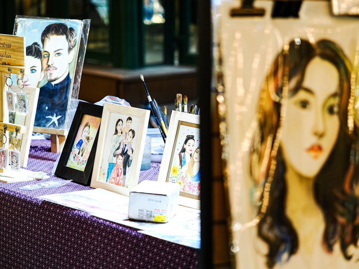 Framed portraits displayed on a table at an art stall.
