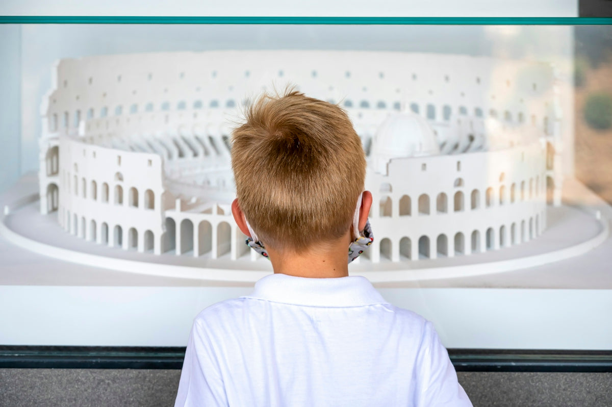 Young boy looking at a white model of the colosseum.
